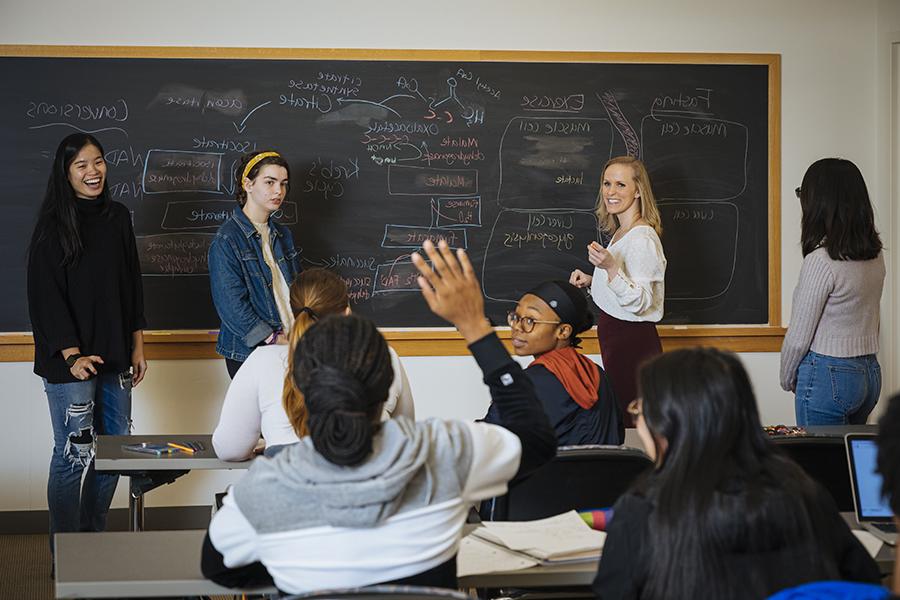 Four students instruct a chemistry workshop at a blackboard